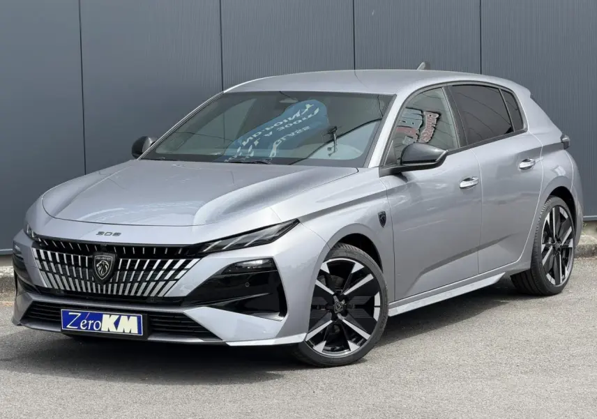 Peugeot 308 gris Artense en 3/4 avant droit, avec calandre distinctive et jantes alliage bi-tons.