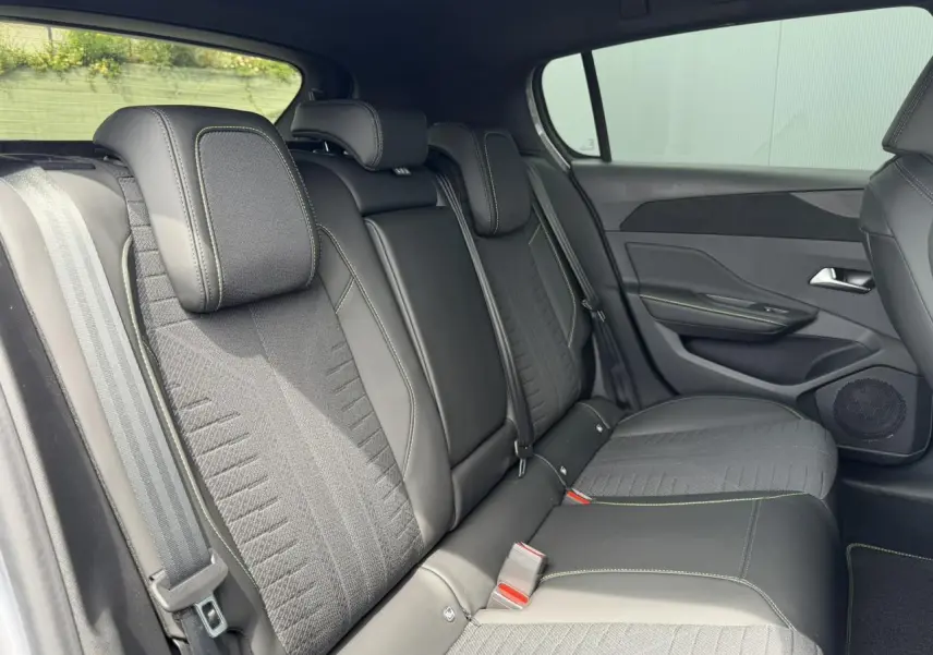 Vue intérieure des sièges arrière noirs avec surpiqûres vertes de la Peugeot 308 NV Hybrid 145 GT e-DSC6 2026.