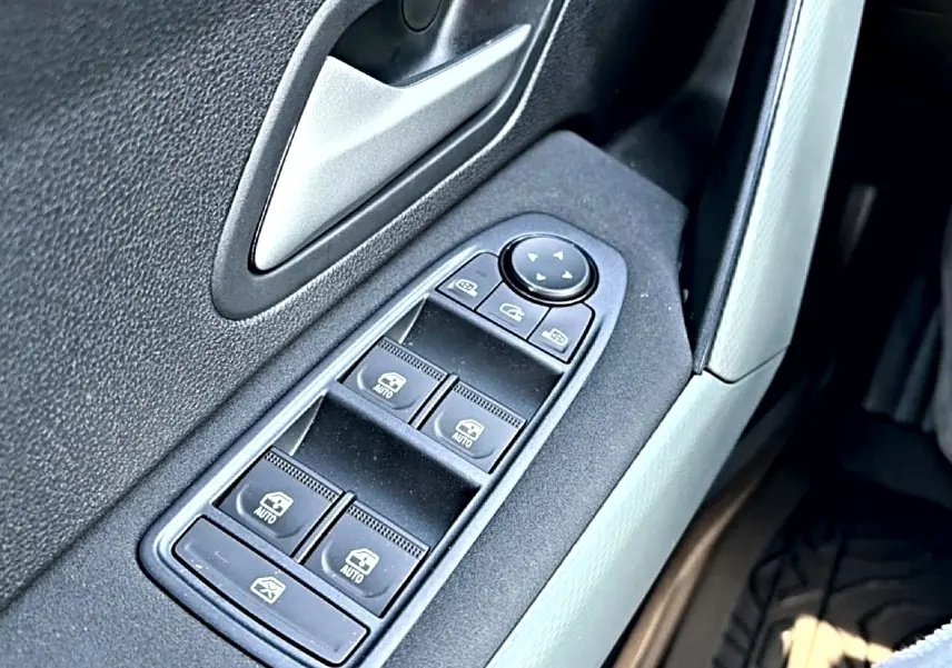 Gros plan sur les commandes des vitres électriques côté gauche d'une Dacia Bigster blanche, intérieur noir et gris.