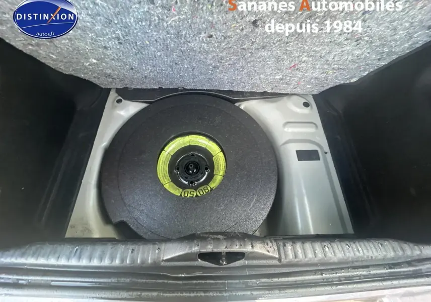 Gros plan sur la roue de secours galette dans le coffre d'une Citroën C3 gris foncé 2023.