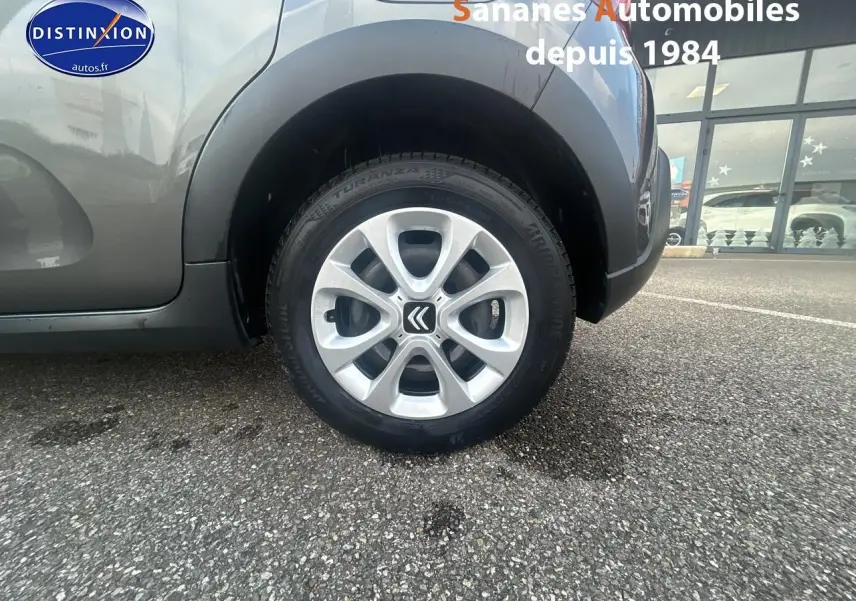 Gros plan sur la roue arrière droite d'une Citroën C3 2023 gris foncé avec jante alliage et logo Citroën central.