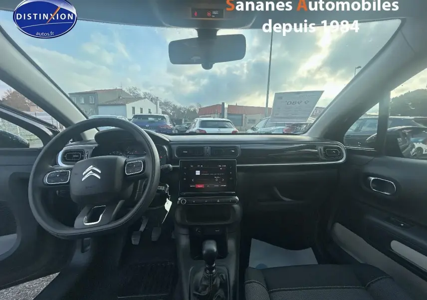 Intérieur de la Citroën C3 2023 gris foncé, vue frontale du tableau de bord avec volant multifonction et écran tactile.