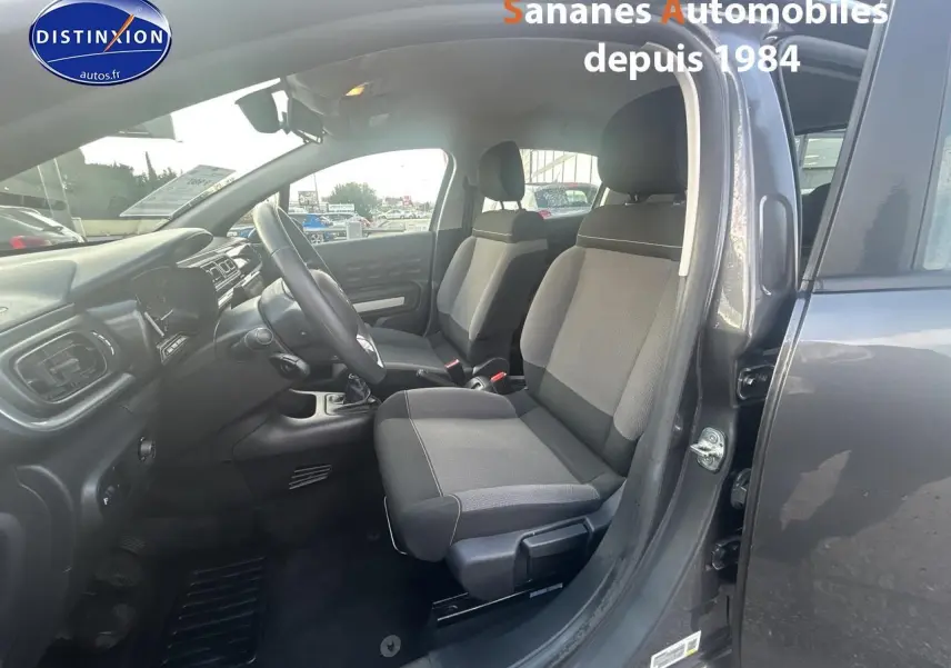 Intérieur côté conducteur d'une Citroën C3 gris foncé 2023, montrant les sièges tissu Mica Grey et la boîte manuelle.