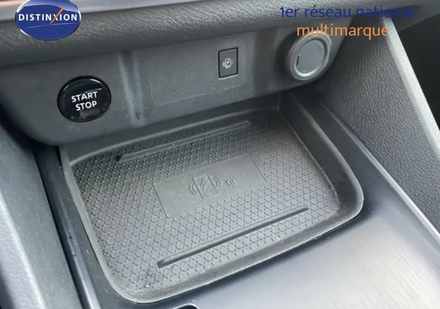 Gros plan sur la console centrale du Nissan Qashqai noir, montrant le bouton Start/Stop et un espace de recharge sans fil.