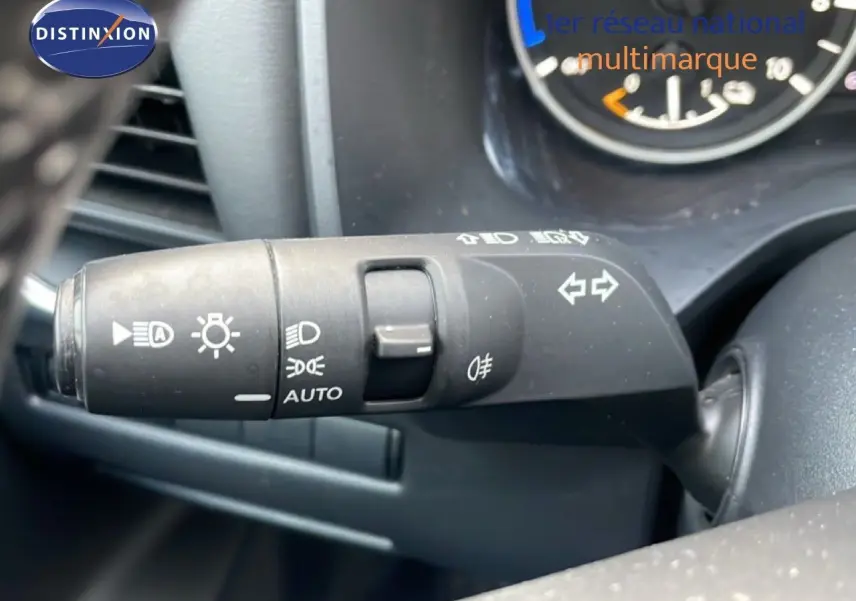 Gros plan sur la commande des feux et clignotants du Nissan Qashqai noir métal, tableau de bord partiellement visible.