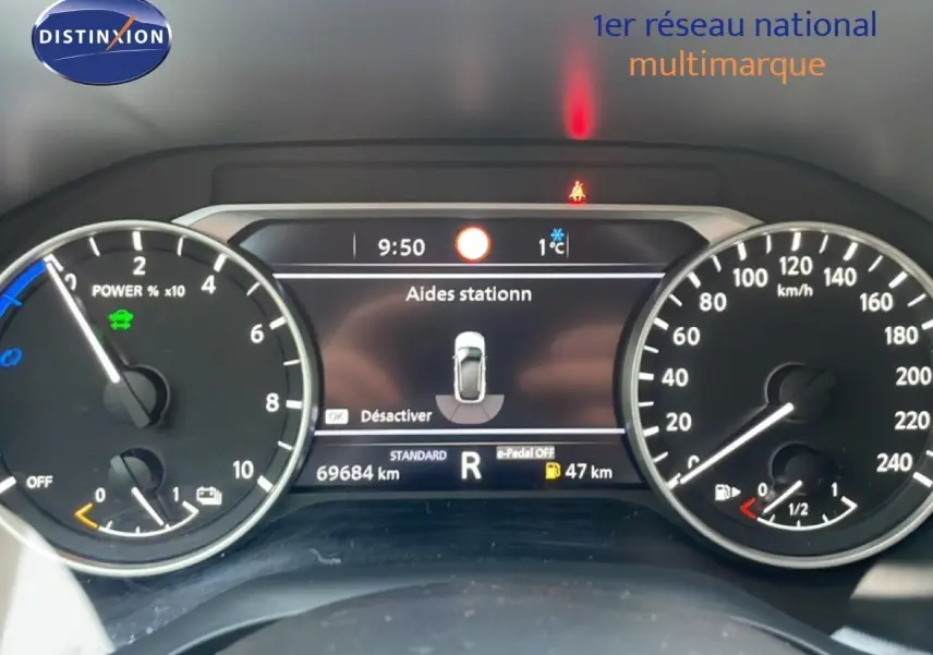 Vue du tableau de bord numérique du Nissan Qashqai 2023 noir métal, affichant l'aide au stationnement et les compteurs.