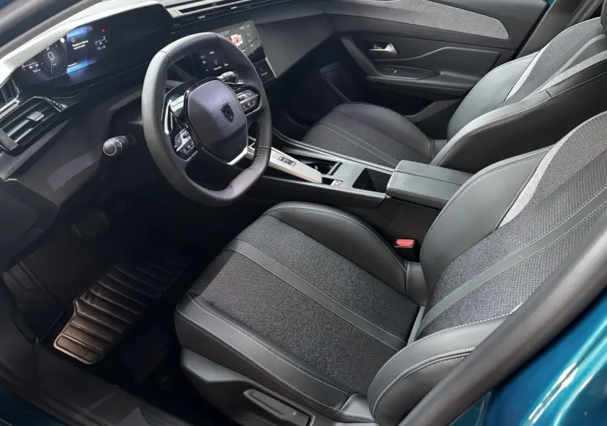 Vue intérieure côté conducteur de la Peugeot 308 Hybrid bleu, volant cuir multifonctions et écran numérique 10 pouces.