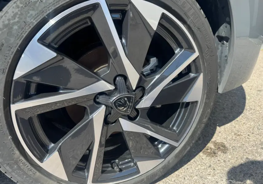 Gros plan sur la jante alliage 17 pouces noire et argentée d'une Peugeot 308 Hybrid gris 2025.