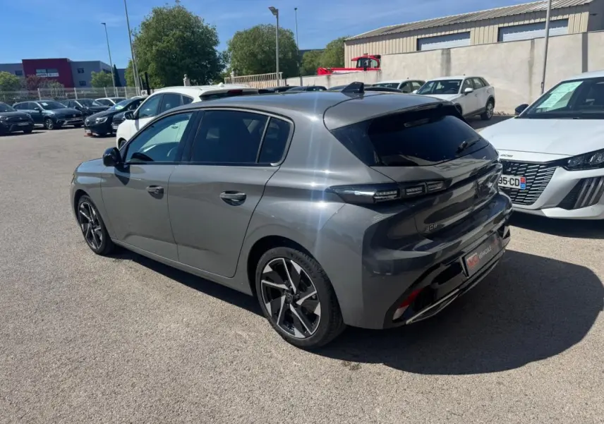 Peugeot 308 Hybrid gris en 3/4 arrière droit, avec jantes alliage 17 pouces et vitres teintées.