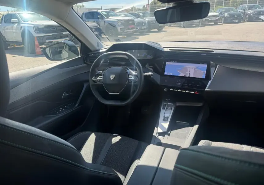 Vue intérieure avant de la Peugeot 308 Hybrid gris, avec volant compact, écran tactile central et cockpit numérique.