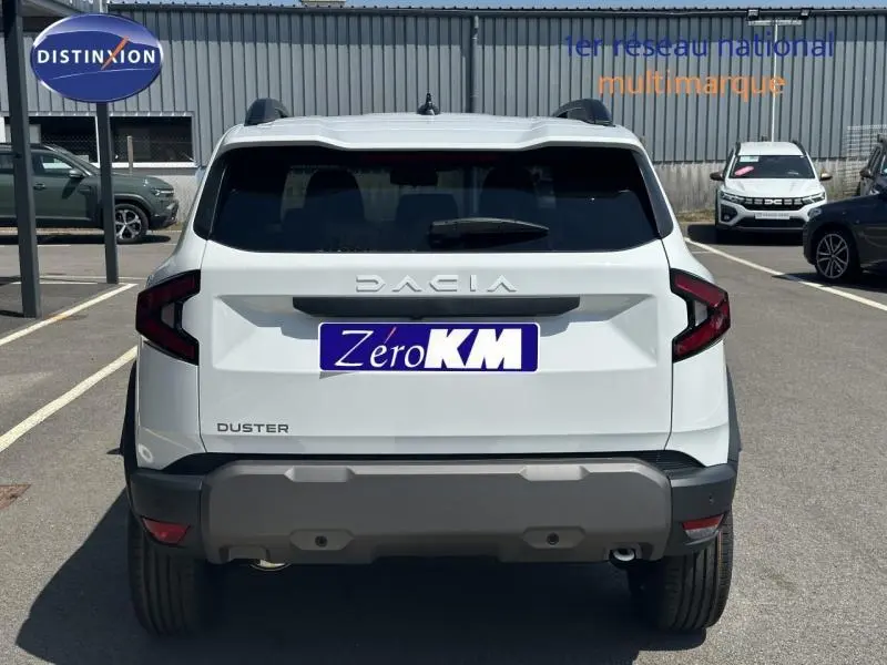 Vue arrière d'un Dacia Duster blanc Glacier 2025 avec feux arrière LED et barres de toit visibles.