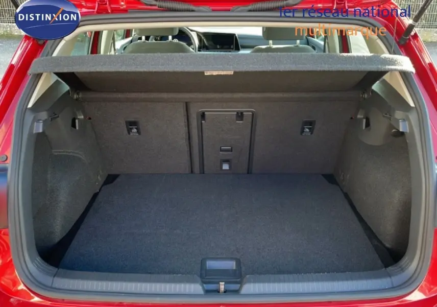 Vue arrière du coffre ouvert d'une Volkswagen Golf VIII rouge Roi Metal, montrant un espace de chargement propre et bien fini.