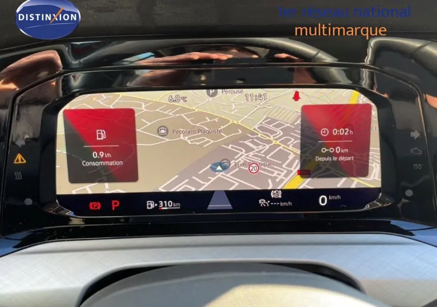 Vue rapprochée de l’écran numérique du tableau de bord de la Volkswagen Golf VIII rouge, affichant la navigation et la consommation.