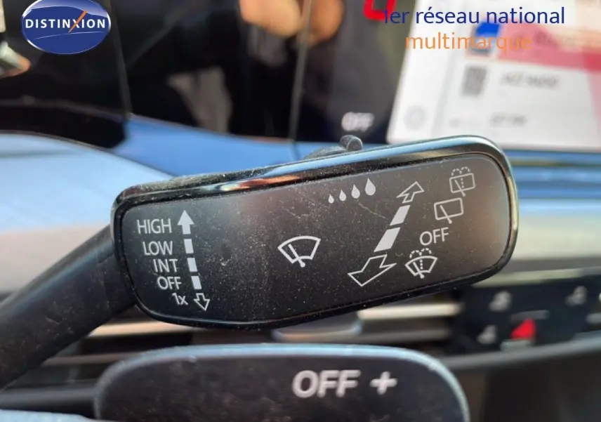 Gros plan sur la commande d’essuie-glace dans l’habitacle d’une Volkswagen Golf VIII rouge, avec tableau de bord flou en arrière-plan.