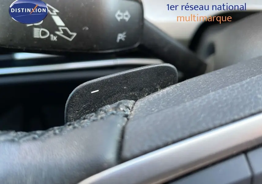 Gros plan sur la palette de changement de vitesse derrière le volant en cuir noir d'une Volkswagen Golf VIII rouge Roi Metal.