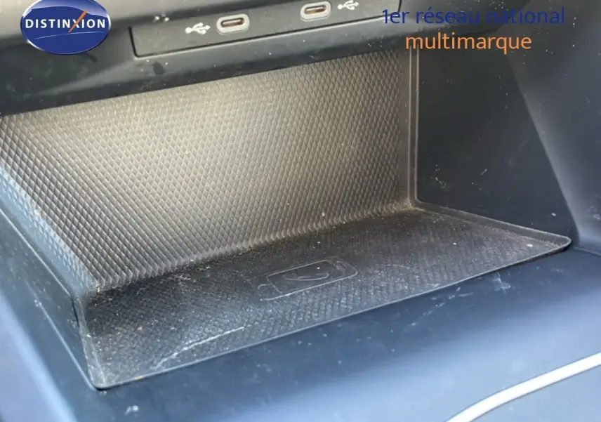 Gros plan sur la console centrale noire de la Volkswagen Golf VIII avec zone de recharge sans fil et ports USB visibles.