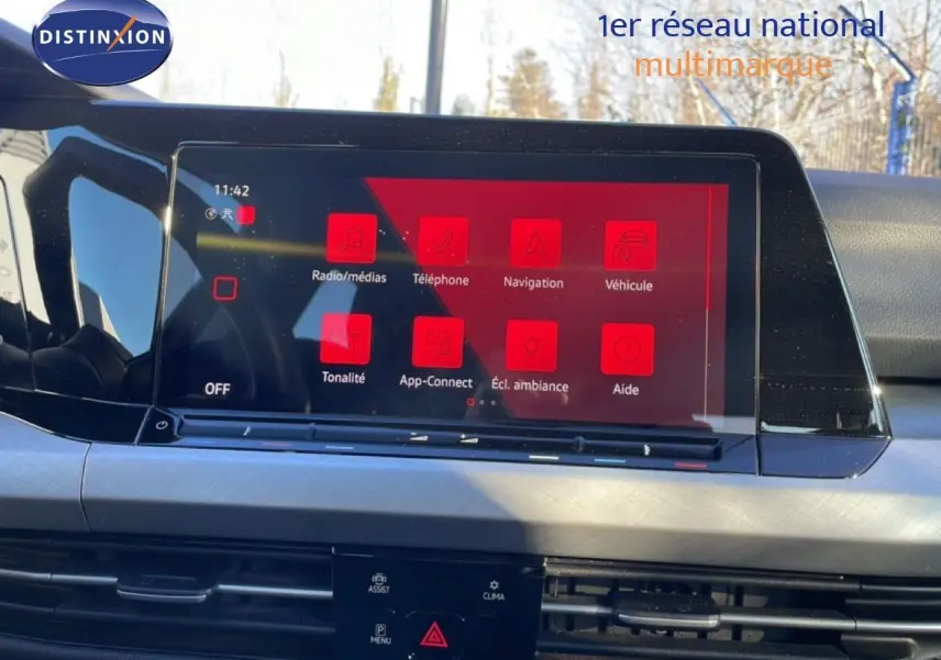 Vue intérieure du tableau de bord de la Volkswagen Golf VIII avec écran tactile affichant le menu multimédia en rouge.