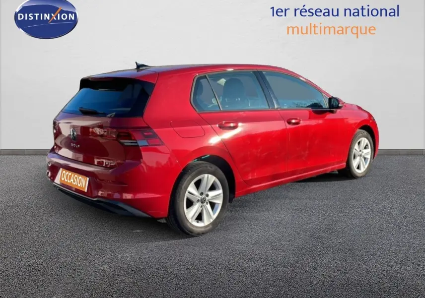Vue 3/4 arrière droite d'une Volkswagen Golf VIII rouge Roi Metal avec jantes alliage et vitres teintées.