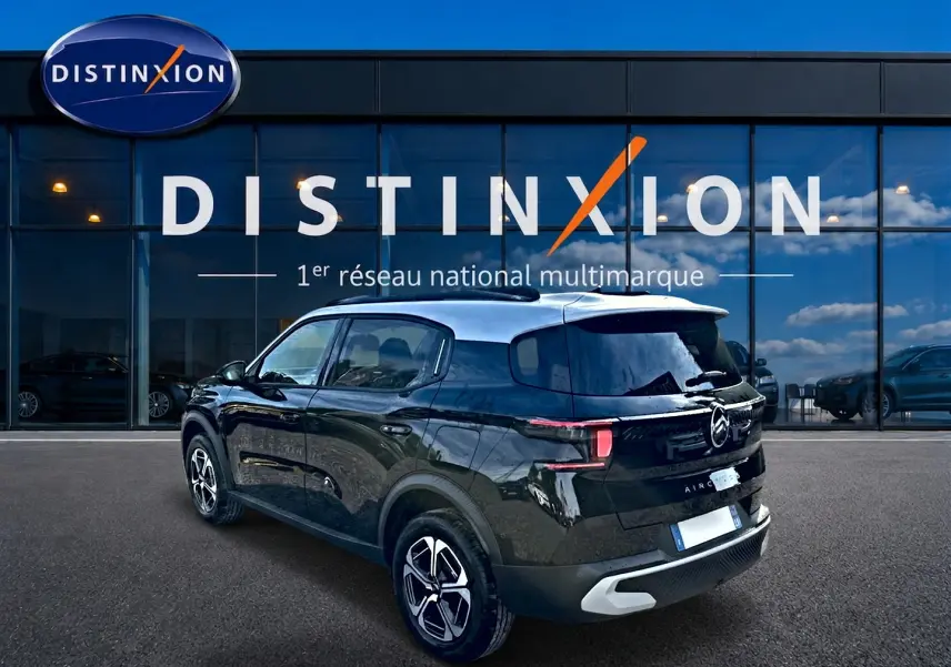 Vue 3/4 arrière droite d'un Citroën C3 Aircross noir 2026 avec toit clair et jantes alu devant un showroom Distinxion.