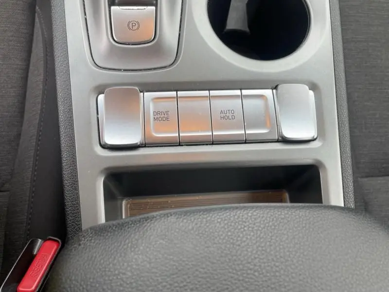 Gros plan sur la console centrale du Hyundai Kona électrique 2021, boutons Drive Mode et Auto Hold visibles, intérieur gris.