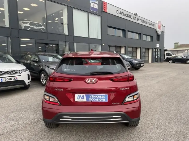 Vue arrière d'un Hyundai Kona électrique rouge métal 2021, avec logo et plaque "Véhicules Occasions" visible.
