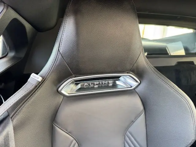 Gros plan sur le siège en cuir noir Sabelt avec logo Alpine chromé, intérieur d'une Alpine A110 gris acier Heritage 2021.