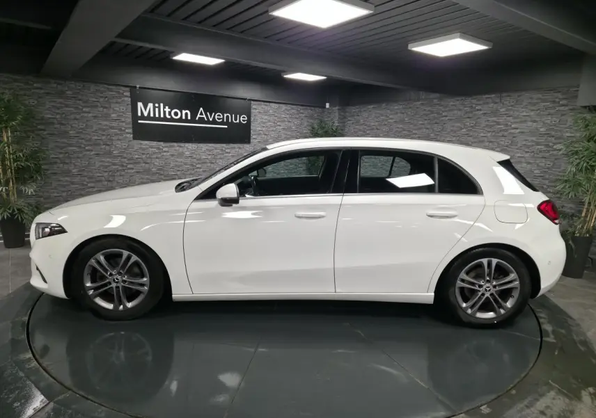 Profil côté gauche d'une Mercedes Classe A blanche 2019 avec jantes alliage 17 pouces dans un showroom.