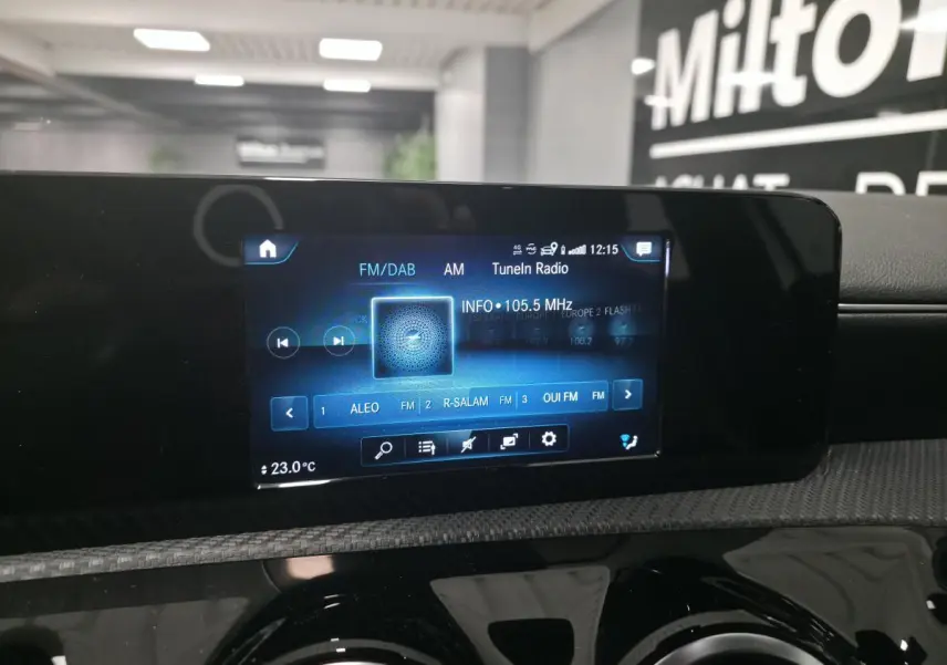 Écran tactile multimédia MBUX affichant la radio FM/DAB dans l'habitacle d'une Mercedes Classe A blanche.