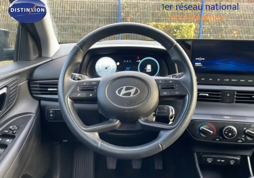 Vue intérieure centrée sur le volant de la Hyundai i20 2025, avec tableau de bord numérique et écran tactile.