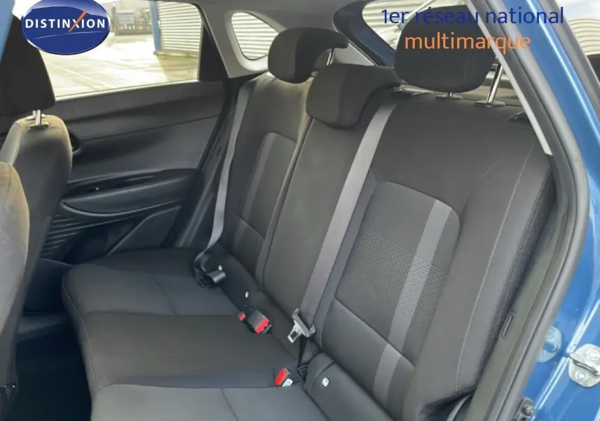 Vue intérieure montrant la banquette arrière noire de la Hyundai i20 2025, porte arrière droite ouverte bleu vibrant métal.