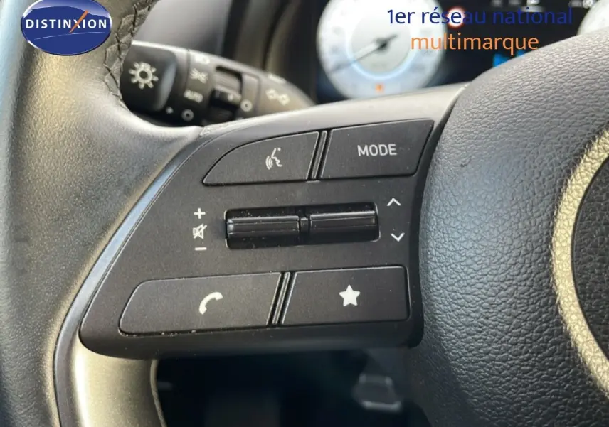 Gros plan sur les commandes au volant noir de la Hyundai i20 2025 Bleu Vibrant Metal, avec boutons de volume et mode.