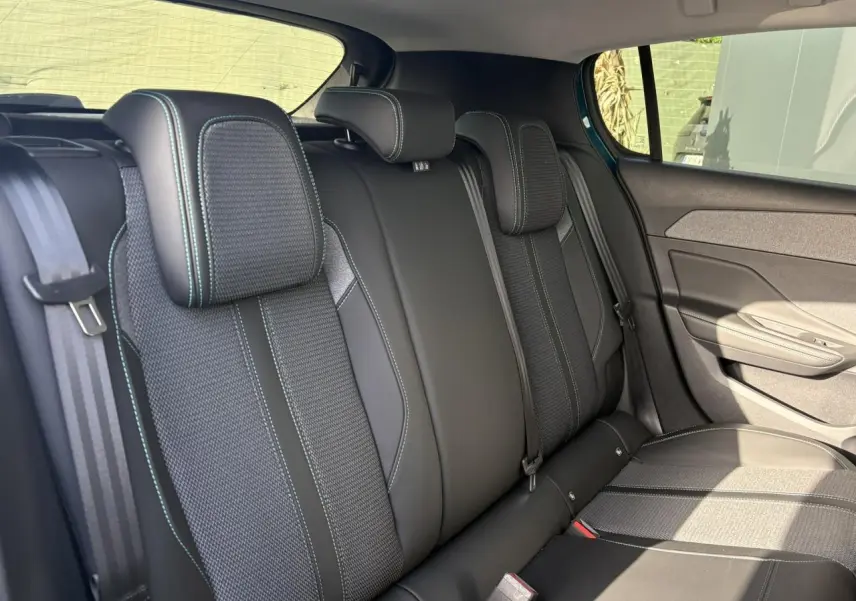 Vue latérale droite des sièges arrière en tissu et cuir noir avec surpiqûres vertes de la Peugeot 308 Hybrid 2025.