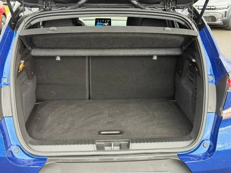 Coffre ouvert en vue arrière d’un Renault Captur 2025 bleu Iron/Noir Étoilé, montrant l’espace de chargement vide.