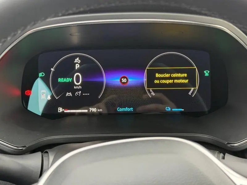 Tableau de bord numérique du Renault Captur 2025 affichant la vitesse, l'autonomie et un message de sécurité, vue frontale rapprochée.