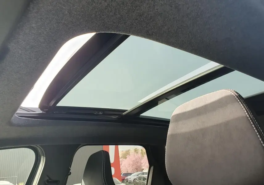 Vue intérieure du toit panoramique ouvert du Dacia Bigster 2026, avec ciel visible et appui-tête avant gris foncé.