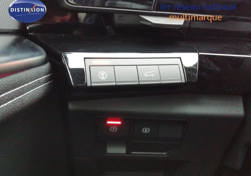 Gros plan sur les commandes intérieures noires brillantes du Renault Austral E-Tech, avec éclairage rouge du frein à main.