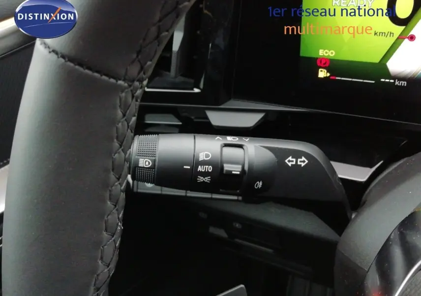 Gros plan sur la commande des feux et clignotants du Renault Austral noir étoile métal, avec tableau de bord numérique en arrière-plan.