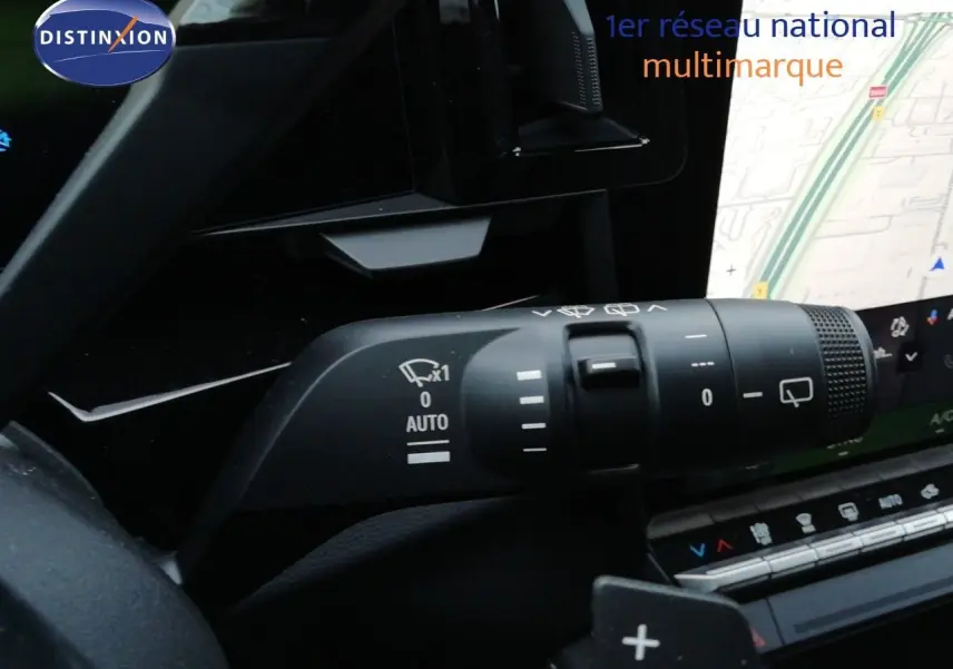 Gros plan sur la commande d’essuie-glace du Renault Austral noir étoile métal, avec écran tactile et carte GPS en arrière-plan.