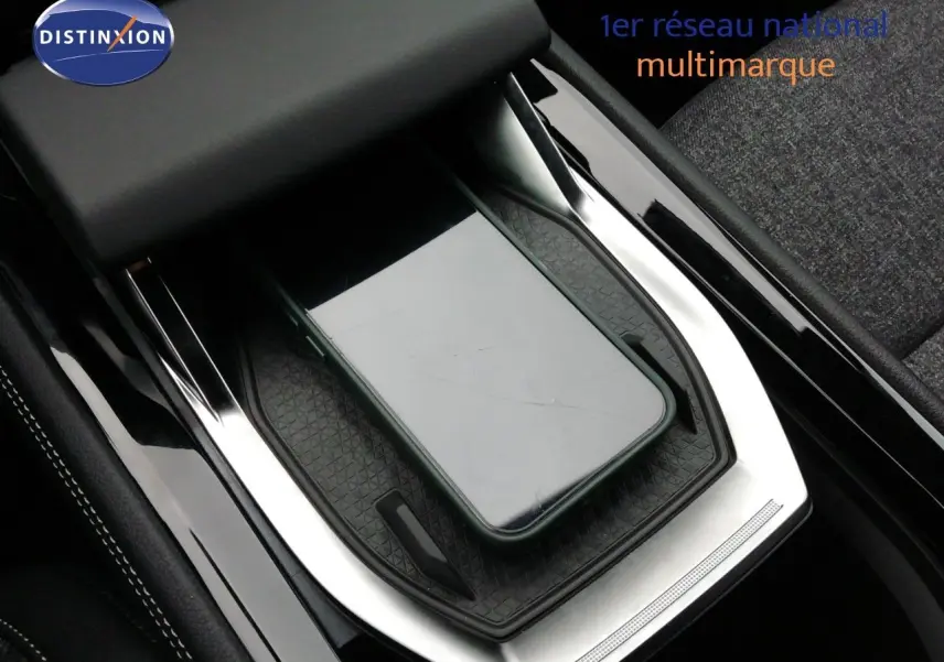 Gros plan sur la console centrale noire et argentée du Renault Austral E-Tech Hybrid avec un smartphone posé dessus.