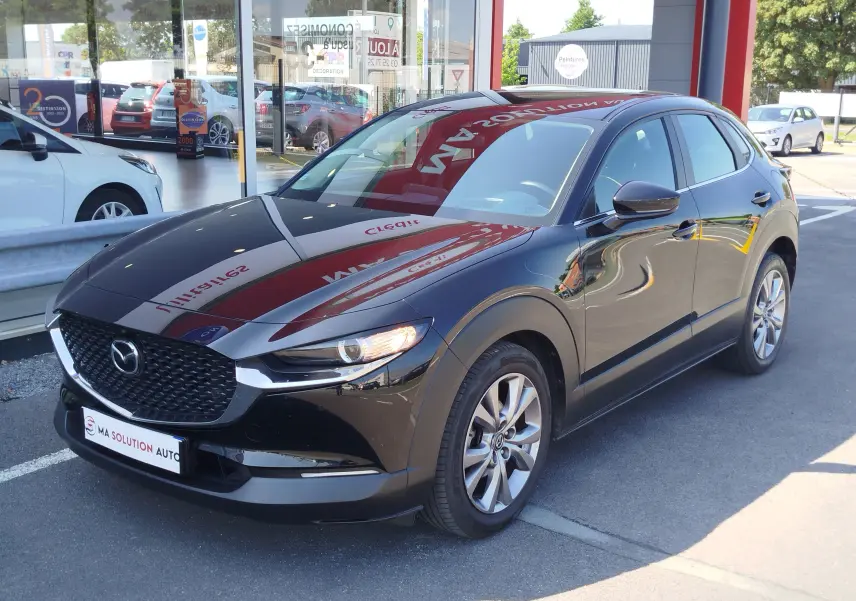 Vue 3/4 avant droite d'un Mazda CX-30 noir brillant, avec calandre imposante et jantes alliage visibles.