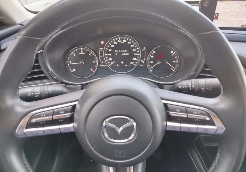 Vue rapprochée du volant noir et du tableau de bord du Mazda CX-30 1.8D 116CH avec affichage digital et commandes intégrées.
