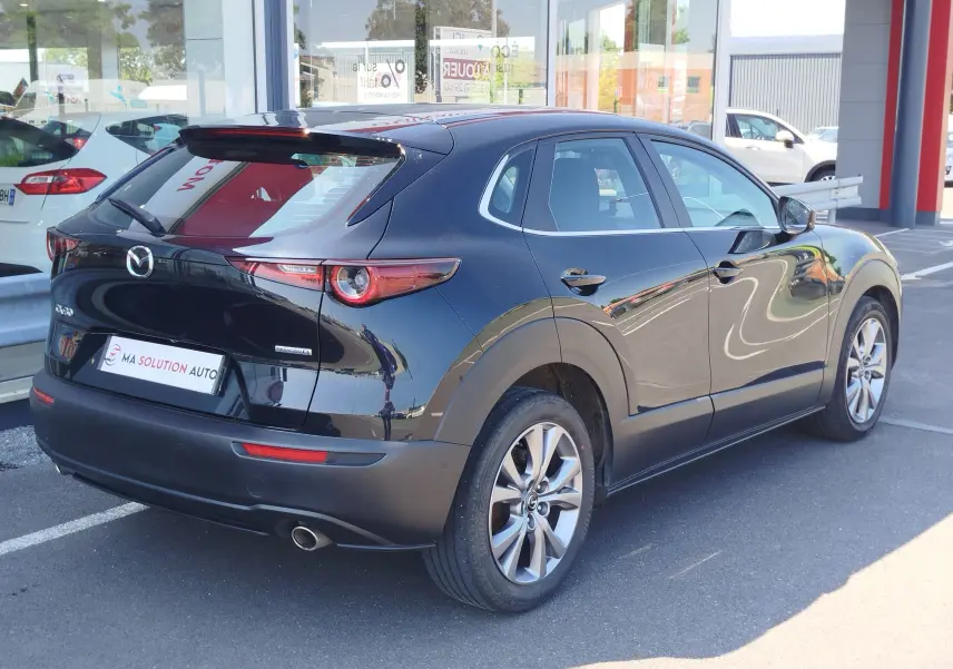Vue 3/4 arrière droite d'un Mazda CX-30 noir 2020 avec feux arrière LED et jantes alliage visibles.