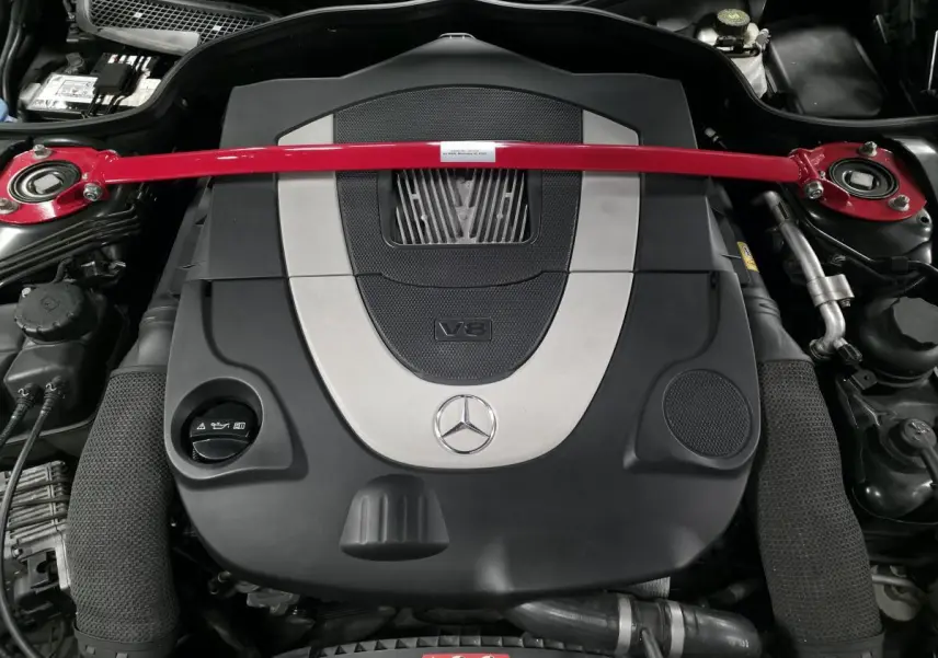 Gros plan sur le moteur V8 Mercedes SL 500 2008 avec barre anti-rapprochement rouge et cache moteur noir et argent.