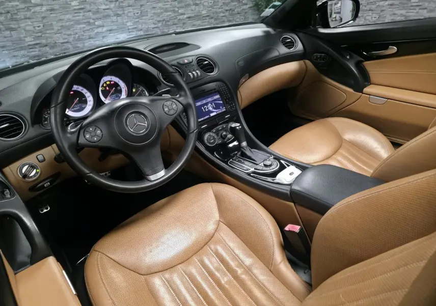 Vue intérieure côté conducteur de la Mercedes SL 500 noire de 2008 avec sièges cuir Nappa beige et console centrale noire.