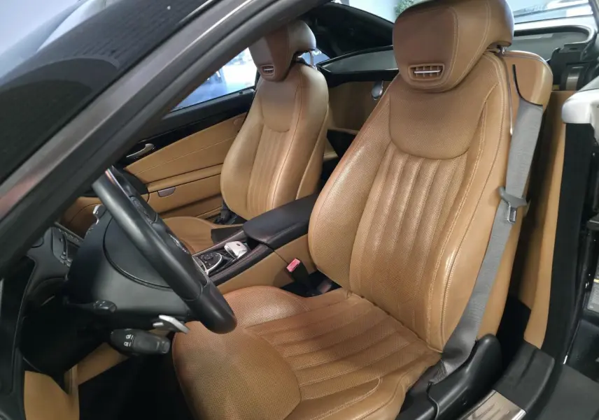 Vue intérieure côté conducteur d'une Mercedes SL 500 noire avec sièges en cuir Nappa marron et volant multifonctions.