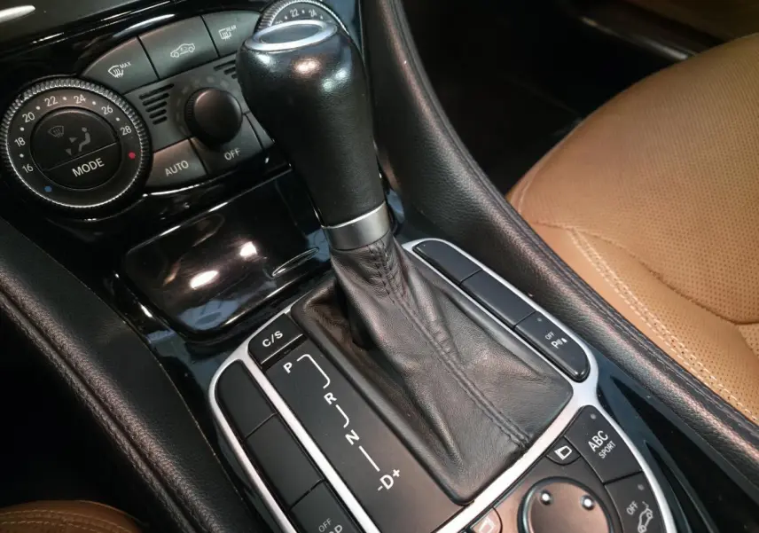 Gros plan sur levier de boîte auto cuir noir et console centrale avec commandes climatisation et siège beige Mercedes SL 500 2008.