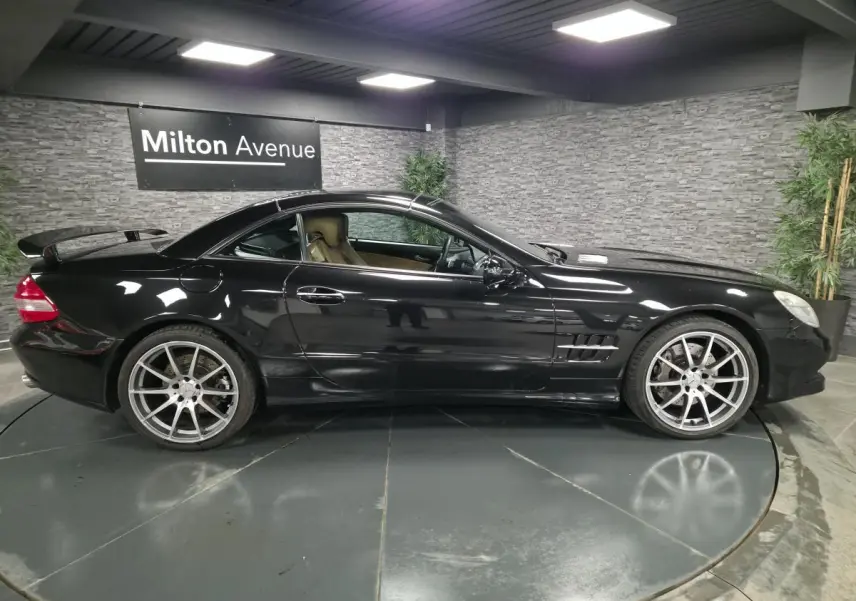 Profil côté gauche d'une Mercedes SL 500 noire de 2008 avec jantes alliage 19 pouces et toit rigide escamotable.