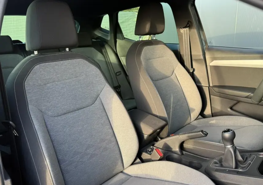 Vue intérieure rapprochée des sièges avant gris clair et console centrale d'une SEAT Ibiza TSI 115 Xcellence 2025 avec boîte manuelle.