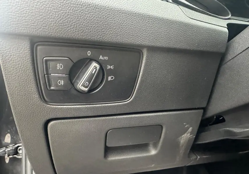 Gros plan sur le bouton de commande des phares sur la planche de bord noire d'une Volkswagen Passat gris foncé 2021.