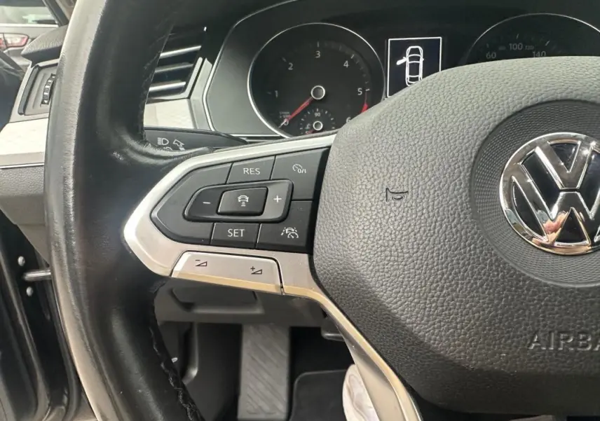 Gros plan sur le volant multifonctions en cuir de la Volkswagen Passat Business 2021 avec commandes au volant visibles.